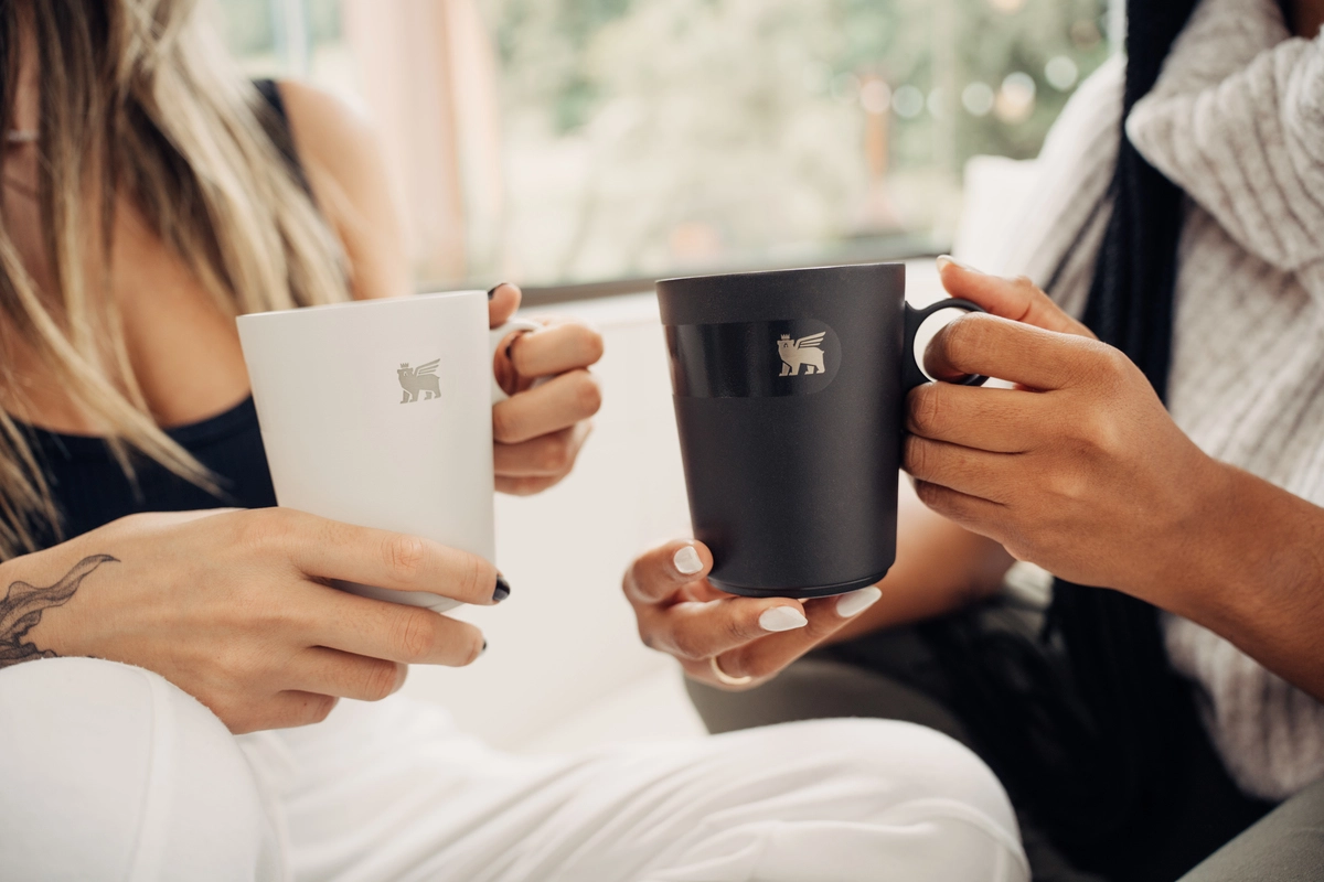 Duas mulheres segurando modelos de caneca de café Stanley