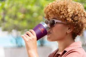 Uma mulher usando o copo Stanley para ingerir bebidas de primavera e se refrescar.