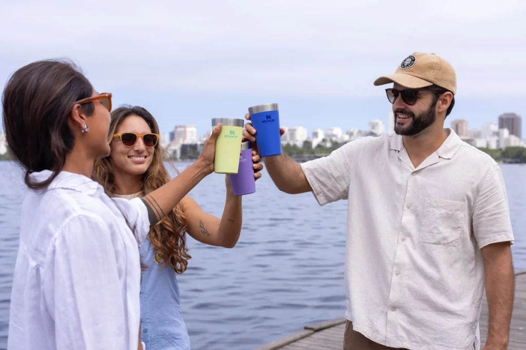 Três amigos com os copos levantados, brincando e celebrando a Black Friday Stanley 2024