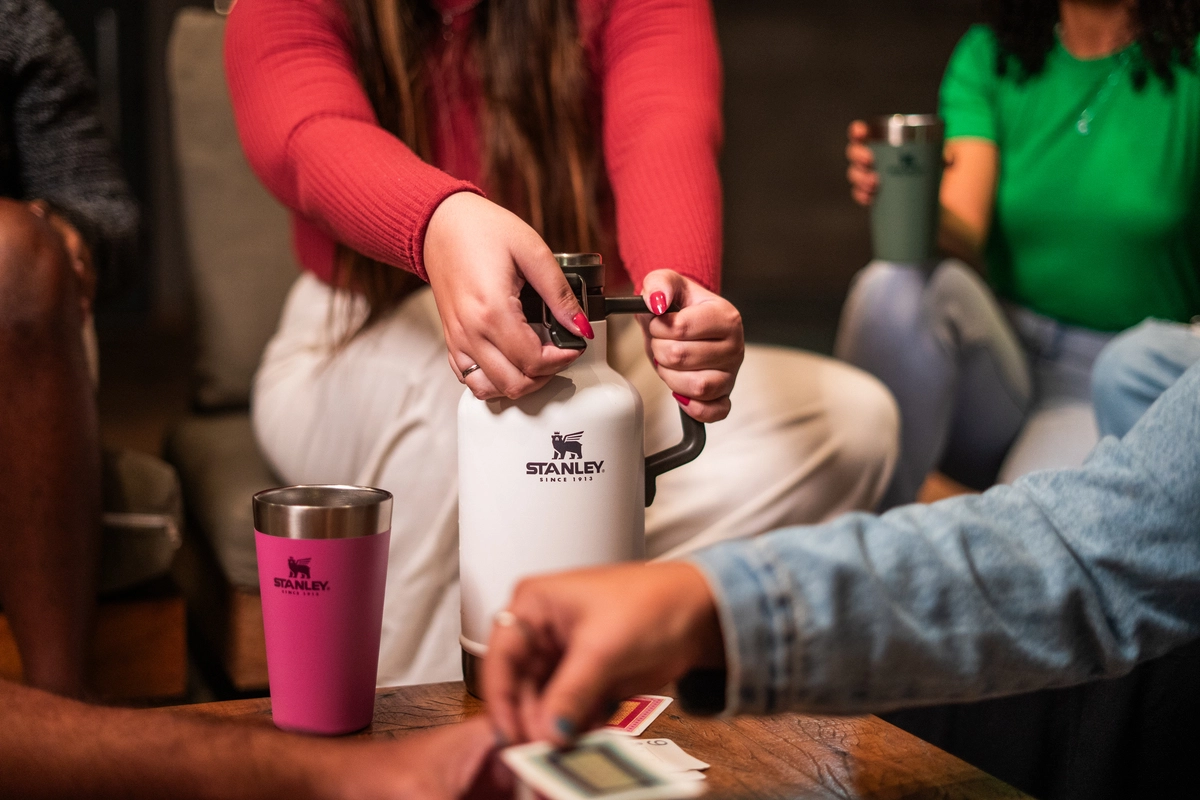 Uma pessoa segurando o Growler térmico, adquirido durante a promoção Stanley Oktoberfest, no meio de uma roda com amigos.